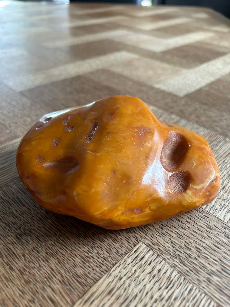 Echtes butterscotch-honigfarbenes Bernstein-Sammlerstück mit polierter Oberfläche und natürlichen Patina-Spuren, auf gewobenem Parkett-Hintergrund, Marcels Sammler-Setting