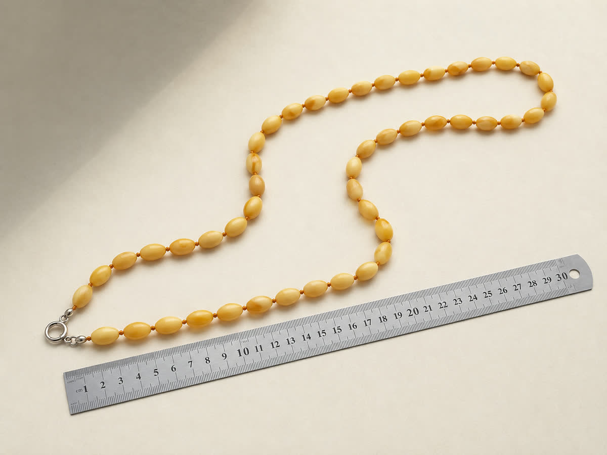 Antike SBM-Olivenkette flach in offener S-Kurve auf cremefarbenem Papier ausgelegt, daneben ein 30-cm-Metalllineal als Längenreferenz, Verschluss-Detail sichtbar