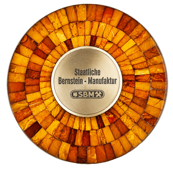 Original-Branding-Disk der Staatlichen Bernstein-Manufaktur Königsberg — radial angeordnete Bernstein-Segmente in Honig- und Cognactönen um eine zentrale Metall-Plakette mit Inschrift „Staatliche Bernstein-Manufaktur