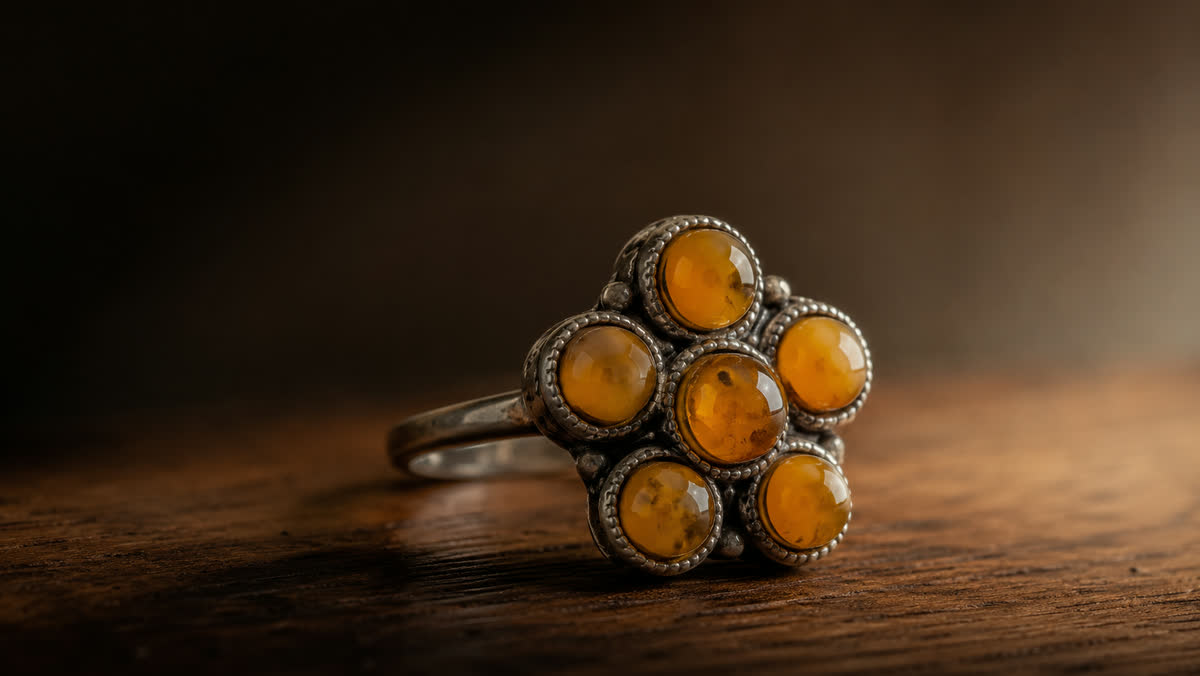 Antiker Cluster-Ring 1920er Jahre mit sechs butterscotch-Bernstein-Cabochons in Blütenform angeordnet, Silberfassung mit Millegrain-Rändern auf dunklem Walnussholz