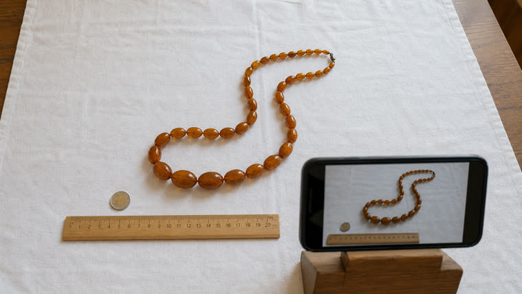 Smartphone-Foto-Setup mit Bernsteinkette, Lineal und Euromünze als Maßstab